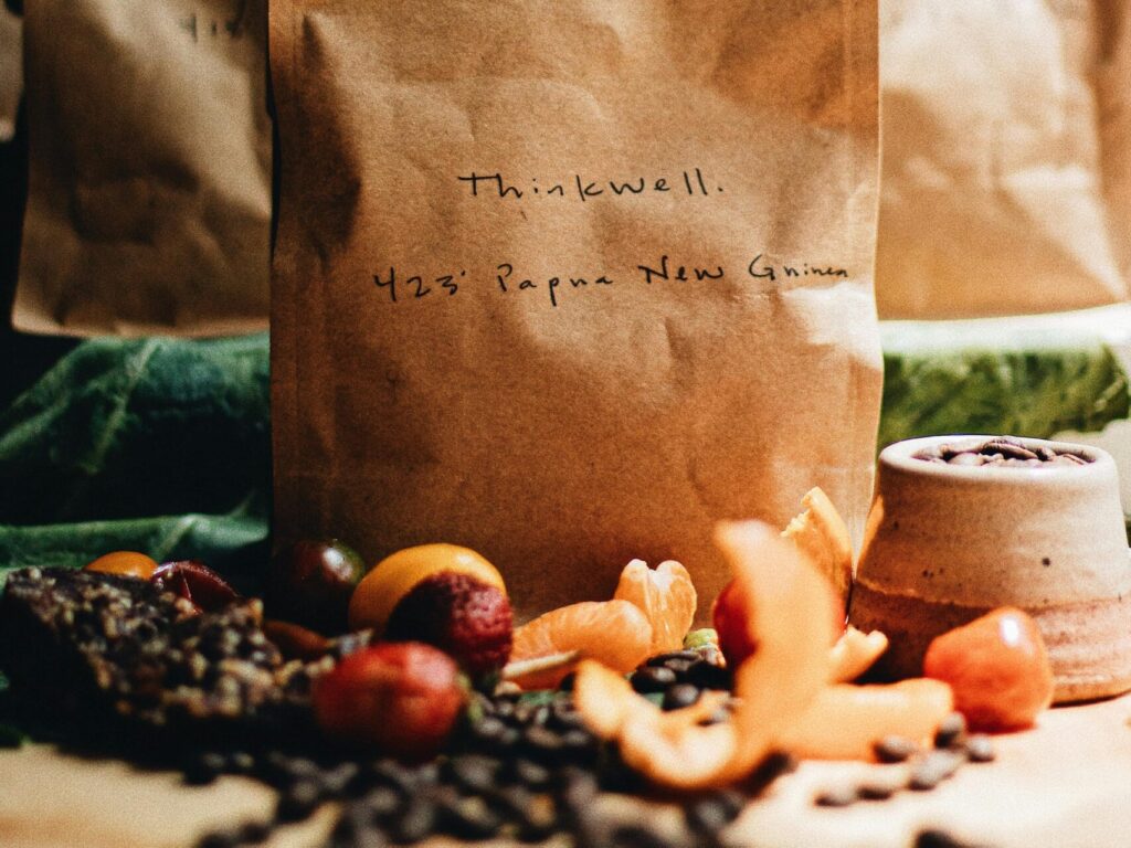Artisan coffee in brown paper bags with fruits and beans. A rustic, warm setup perfect for branding.